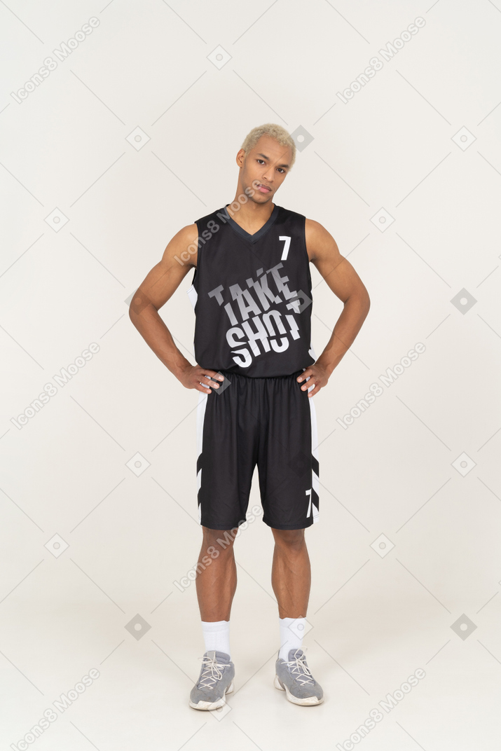 Front view of a young male basketball player putting hands on hips & looking at camera