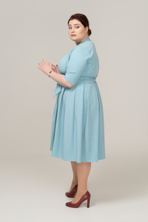 Frau im blauen kleid steht im profil
