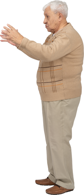 Vista laterale di un uomo anziano in abiti casual che mostra le dimensioni di qualcosa