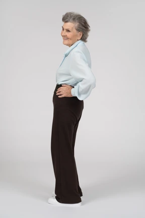 Side view of an old woman smiling with a hand on a hip