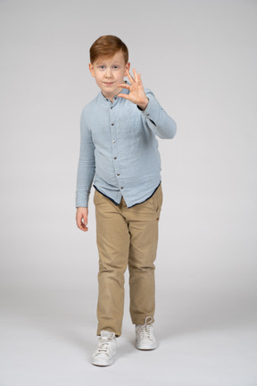 Vista frontal de um menino bonito, mostrando o tamanho de algo e olhando para a câmera
