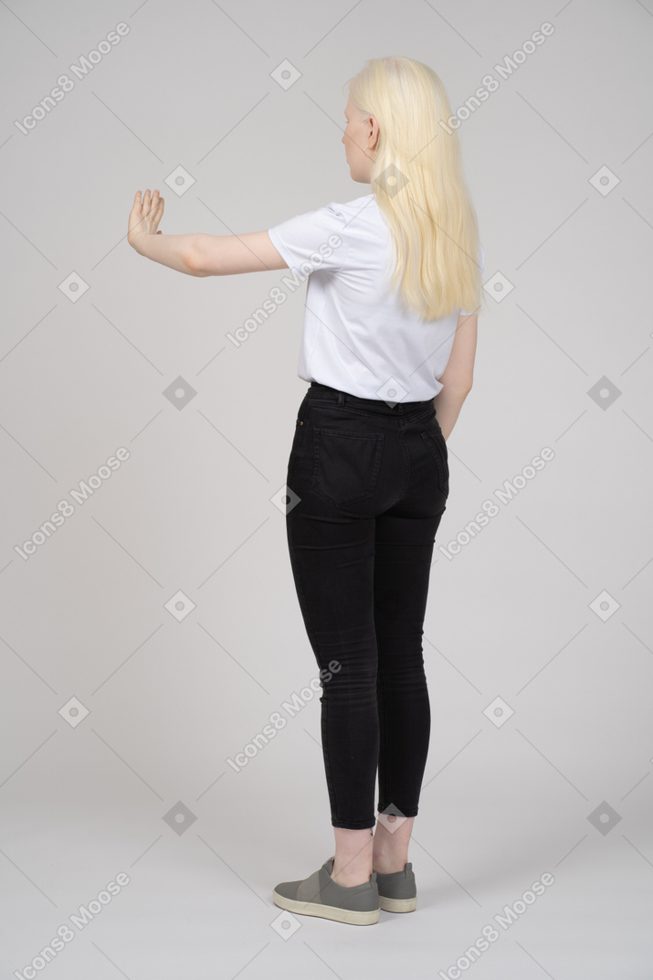 Vista trasera de una joven rubia parada y mostrando su palma