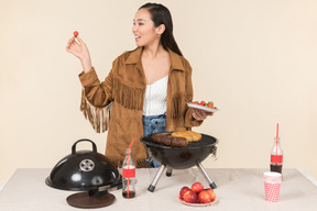 Young asian woman standing near grill and throwing a fruit