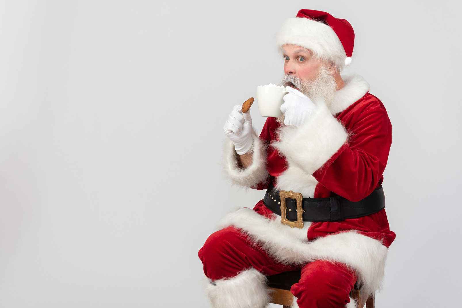 Surprised santa claus drinking tea and eating cookie