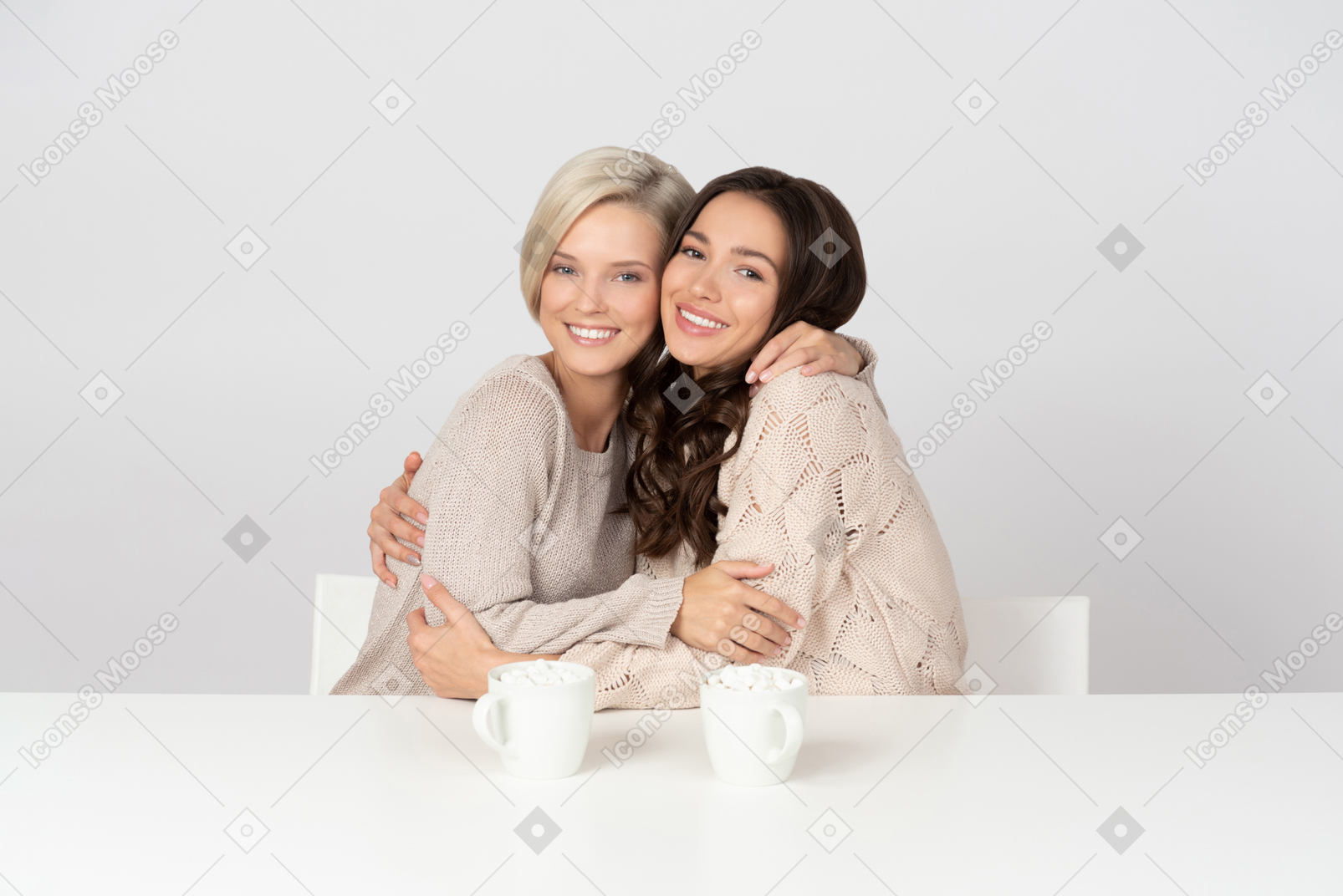 Молодые женщины обнимаются и пьют кофе