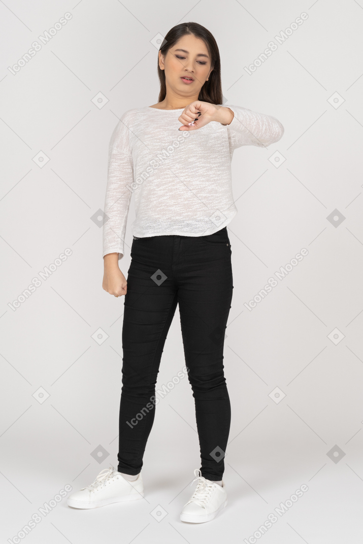 Front view of a young indian female in casual clothes checking time