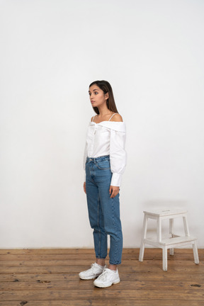 Woman standing on wooden floor in white shirt and jeans