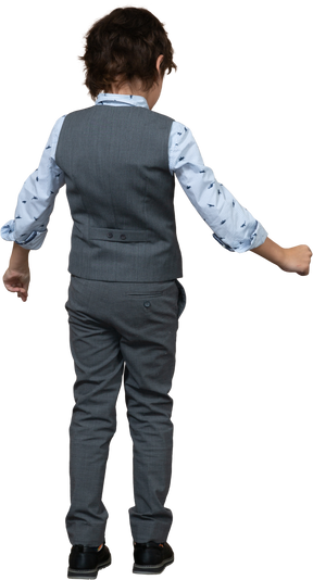Rear view of a boy in suit standing with outstretched arms