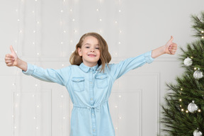 A little girl standing in front of a christmas tree