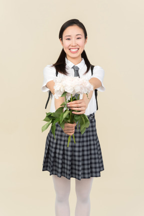 Smiling asian school girl holding flowers