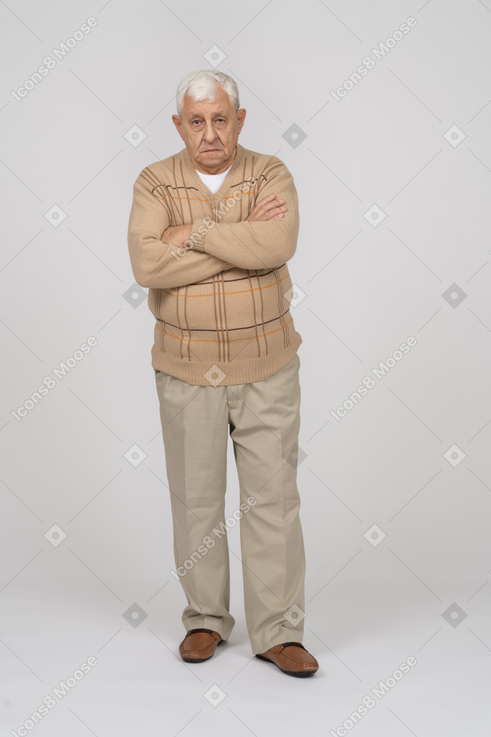 Front view of an old man in casual clothes standing with crossed arms and looking at camera