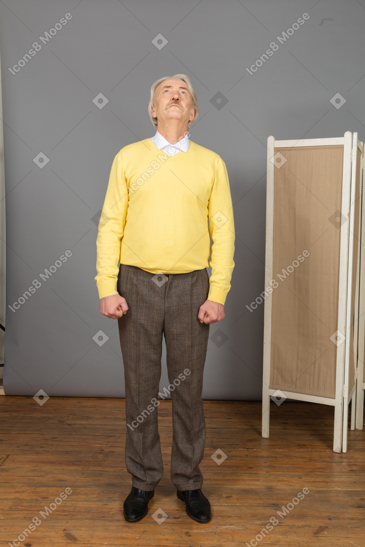 Front view of an impatient old man clenching fists while looking up