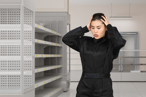 Young woman standing in a supermarket with empty shelves