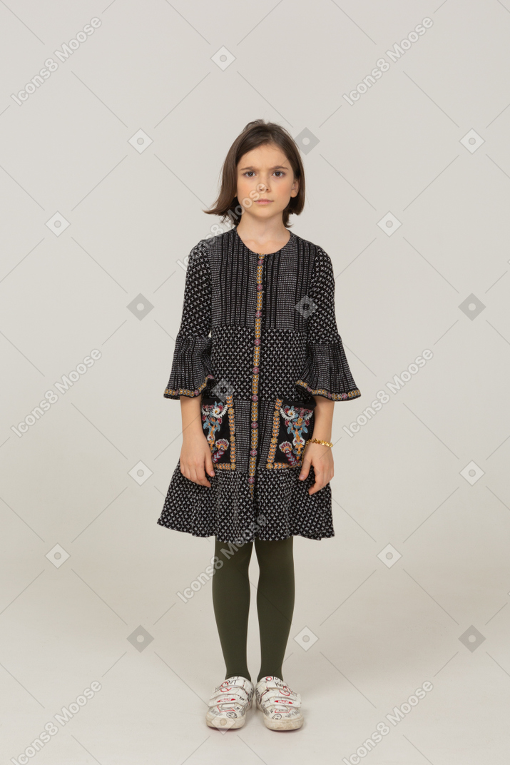 Vista frontal de uma menina intrigada com um vestido tricotando sobrancelhas