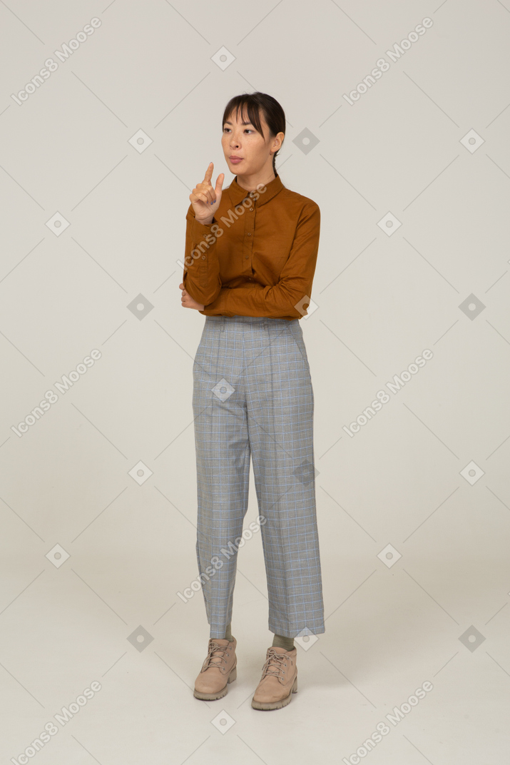 Vista de tres cuartos de una joven mujer asiática en calzones y blusa que muestra el tamaño de algo