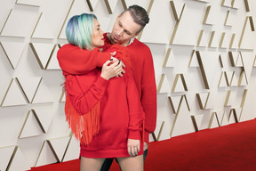 A man and a woman hugging on a red carpet