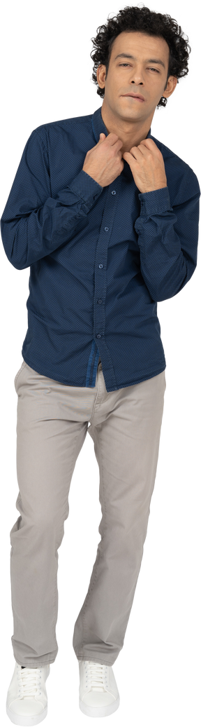 Vista frontale di un uomo in abiti casual che tocca il colletto della camicia