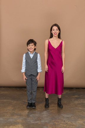 Vista frontal de um menino e uma mulher sorrindo com um vestido vermelho