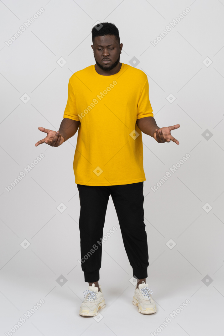 노란 티셔츠를 입은 사려깊은 몸짓을 하는 짙은 피부의 젊은 남자의 전면