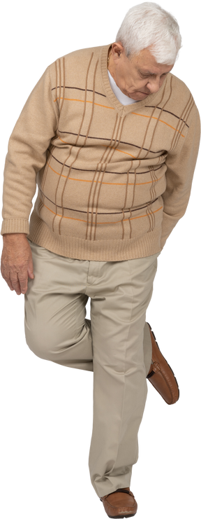 Vista frontal de un anciano con ropa informal parado en una pierna y mirando hacia abajo