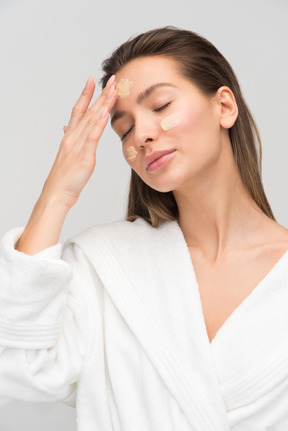 Beautiful young woman applying face cream