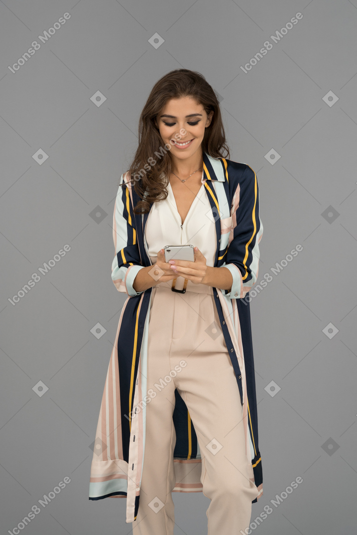 Smiling young woman texting by cellphone