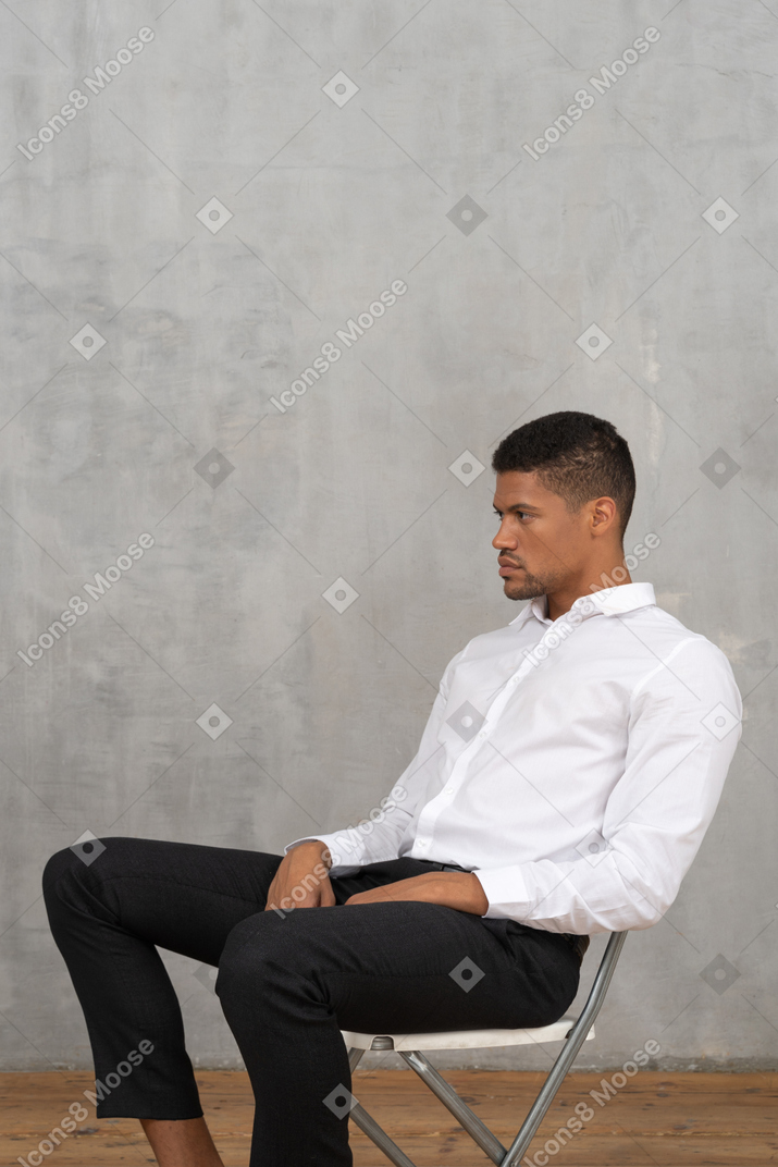 坐在椅子上手放在腿上的男人的侧视图