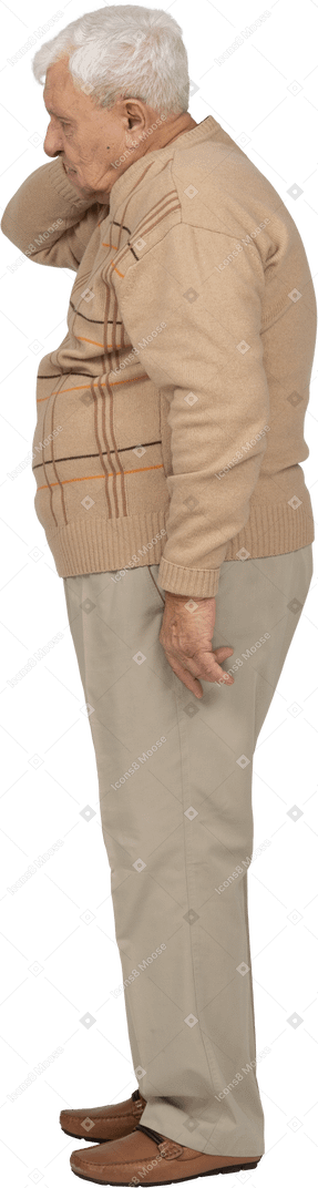 Side view of an old man in casual clothes standing with hand on neck