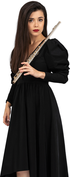 Vista di tre quarti di una giovane donna seria in vestito nero che tiene flauto