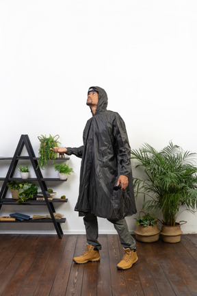 Man in raincoat catching raindrops onto palm