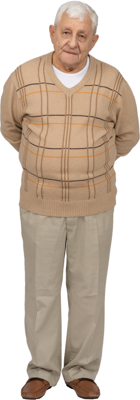 Vue de face d'un vieil homme en vêtements décontractés debout avec les mains derrière le dos