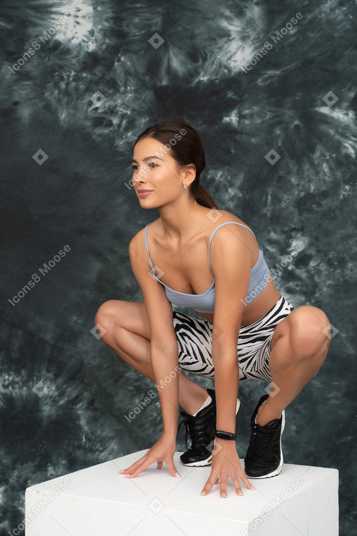 Una atleta femenina sentada a cuatro patas mirando a un lado y sonriendo