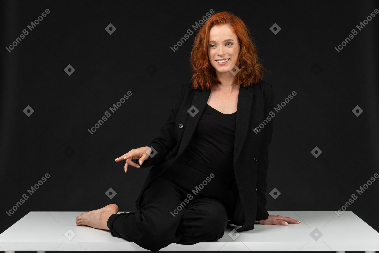 검은 옷을 입고 테이블에 앉아있는 젊은 웃는 여자의 정면보기