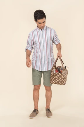 Young guy looking at picnic basket he's holding