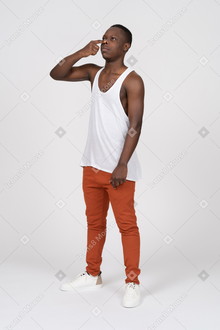 Man in tank top pressing the tip of his nose