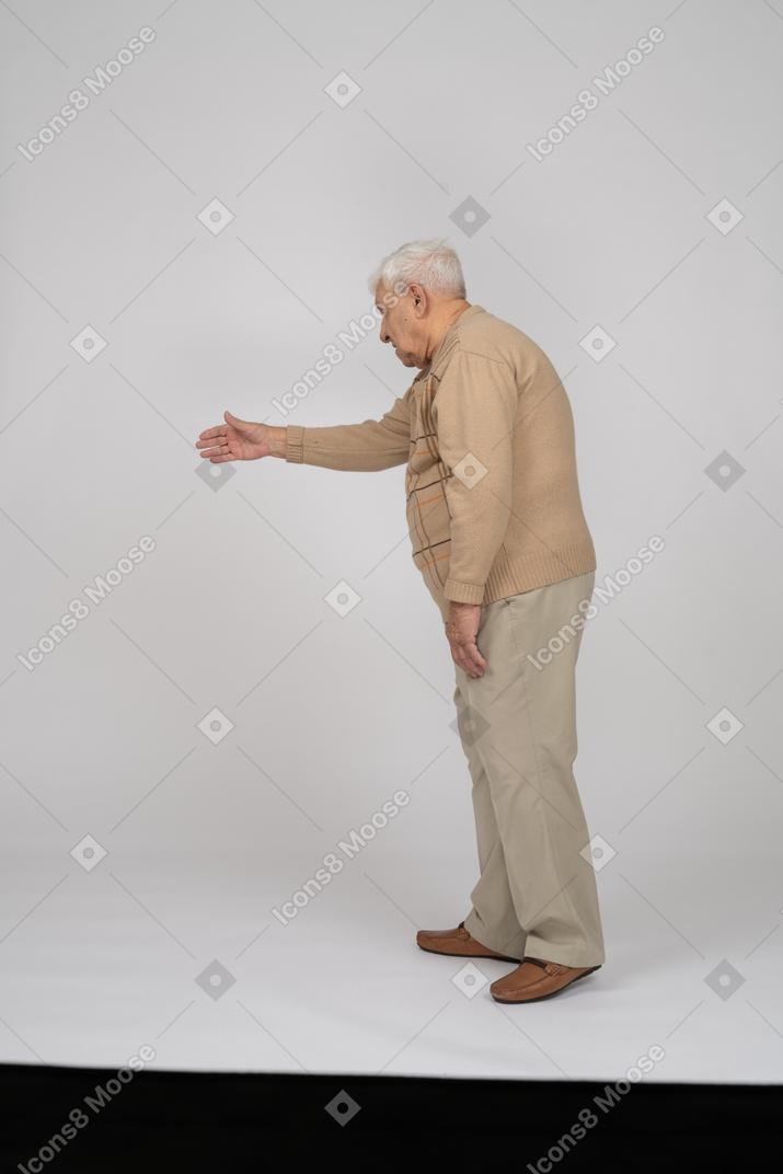 Vue latérale d'un vieil homme en vêtements décontractés donnant un coup de main pour secouer
