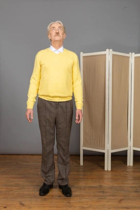 Front view of an old man standing still and looking up