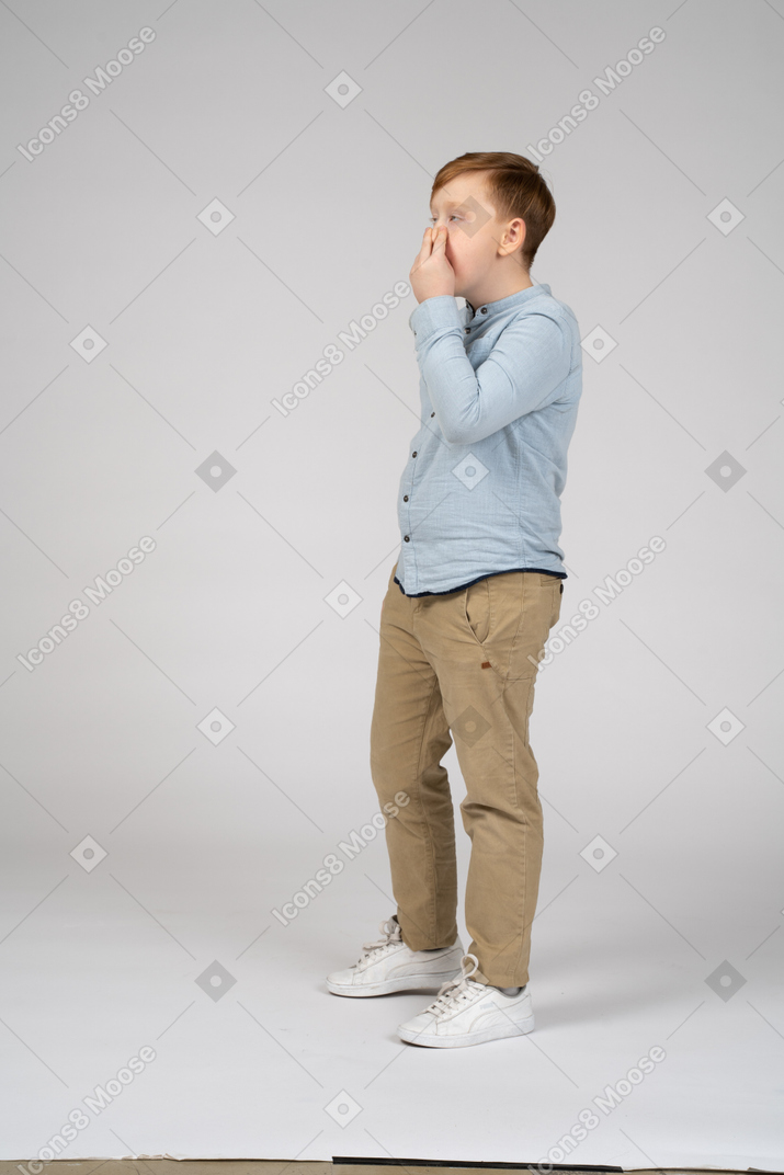 Boy standing and closing his nose