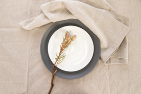 Black and white plates and twig on tablecloth