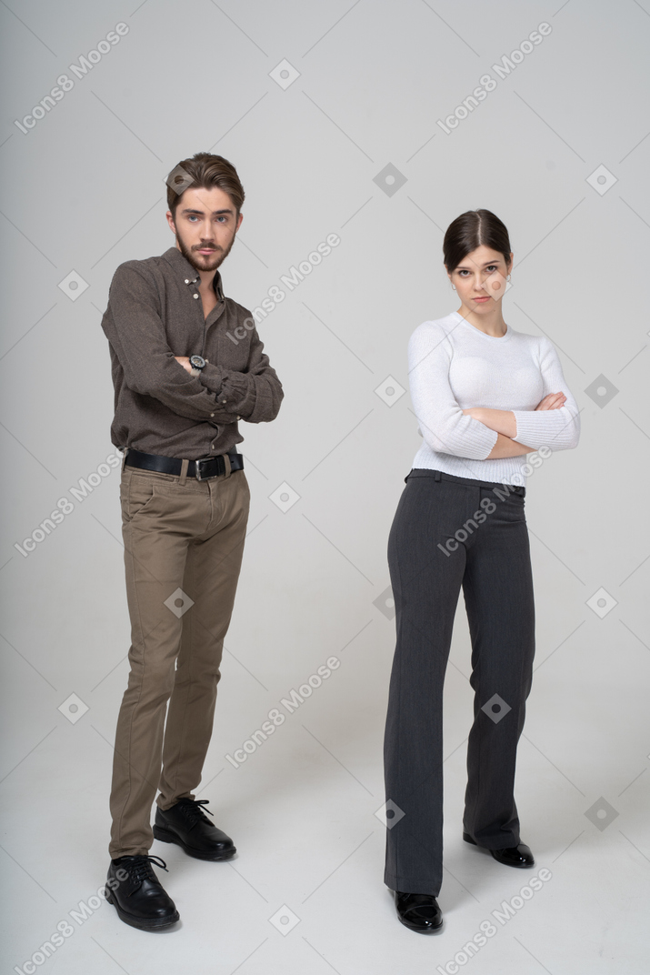 Vista frontal de um jovem casal com roupas de escritório, cruzando os braços