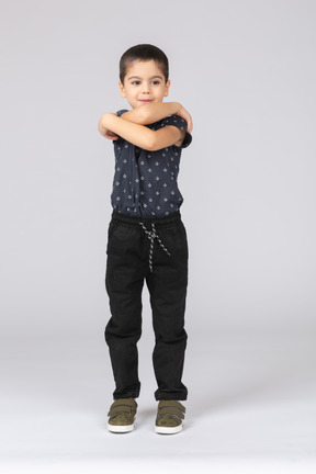 Vue de face d'un garçon mignon debout avec les bras croisés et regardant de côté