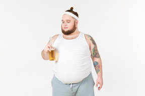 Um homem gordo no sportswear segurando uma garrafa de cerveja