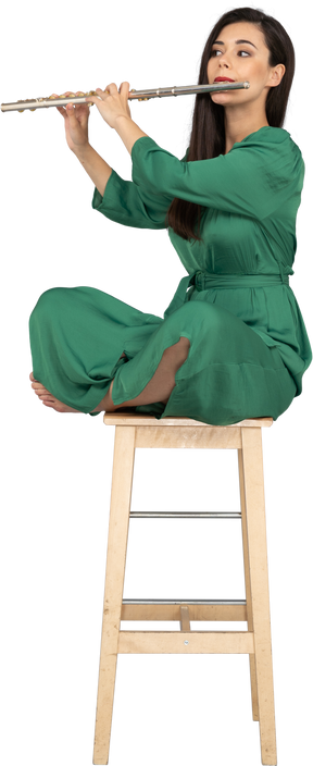 그녀의 다리에 앉아 클라리넷을 연주하는 젊은 아가씨의 전체 길이는 나무 의자에 교차