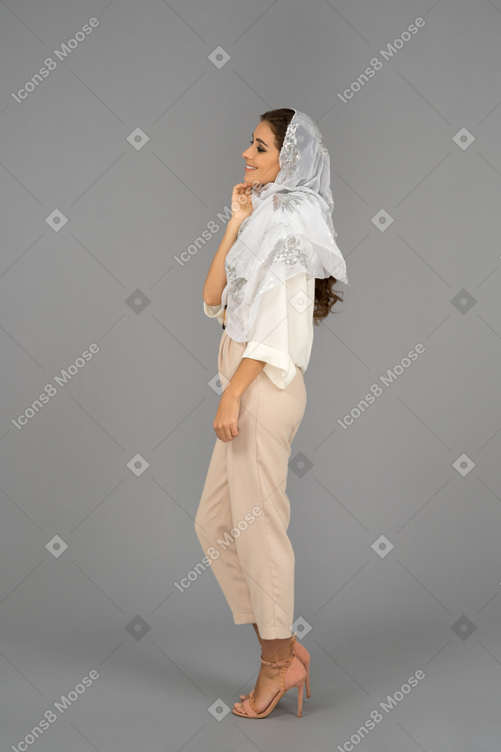 Cheerful covered woman looking aside and touching chin