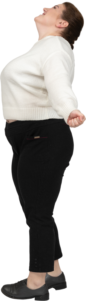 Feliz mujer de talla grande en suéter blanco de pie en el perfil