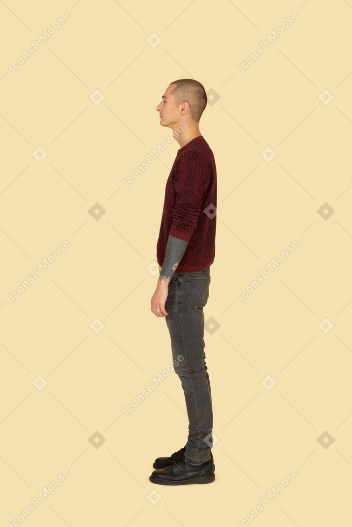 Vista laterale di un giovane uomo in un maglione rosso che osserva da parte