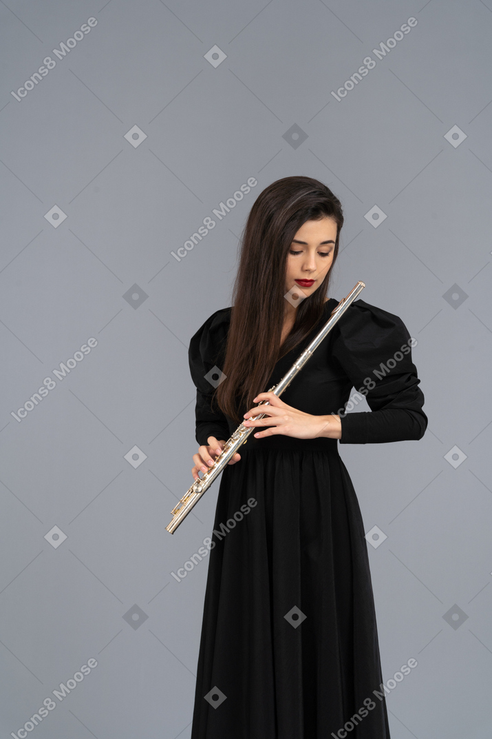 Front view of a serious young lady in black dress holding flute