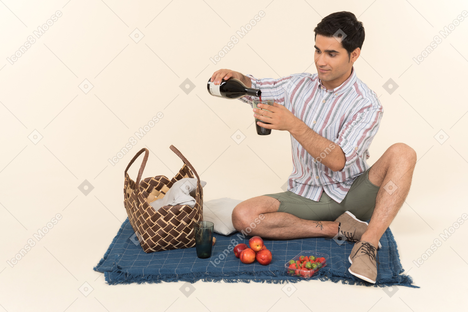 年轻的白种人男子坐在毯子上，倒入玻璃酒