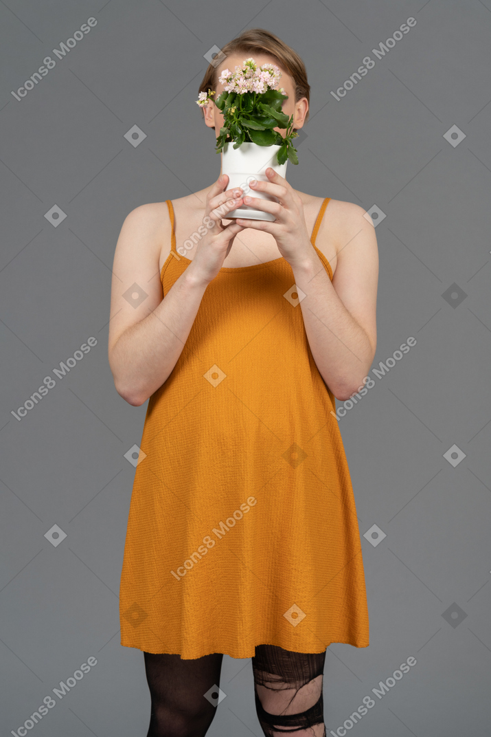 Portrait d'une personne se cachant le visage derrière un pot de fleurs