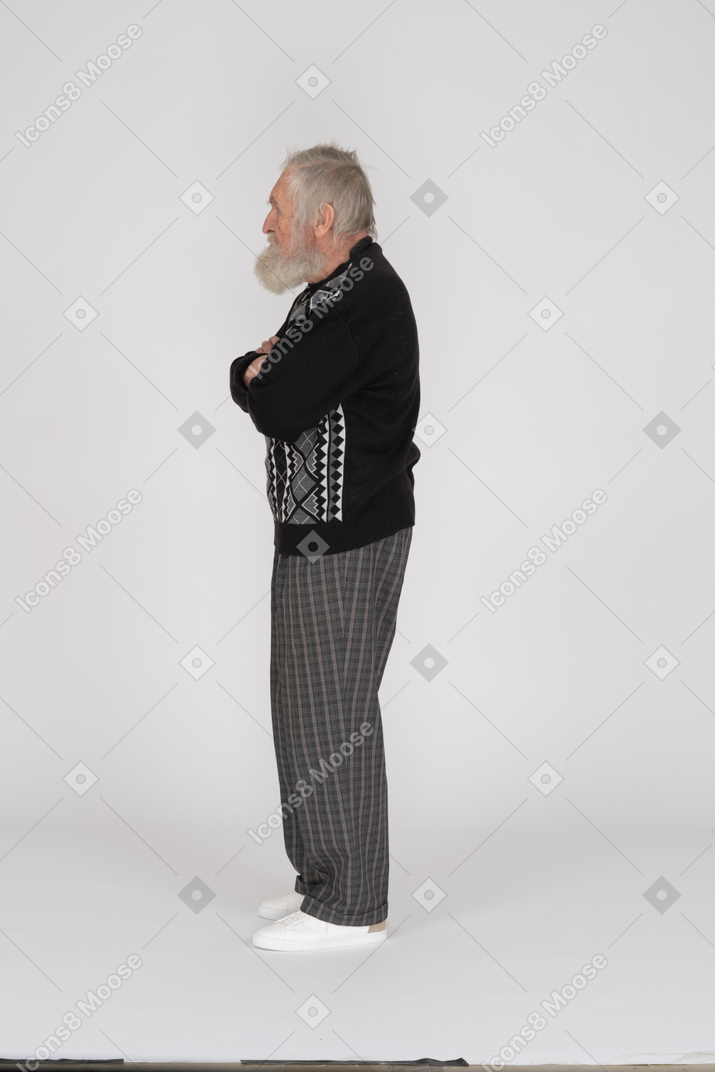 Vista lateral do homem idoso em pé com os braços cruzados
